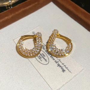 Détail de boucles d'oreilles torsadées en or 18K avec zircons et incrustations brillantes
