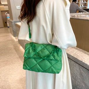 Fashionable green quilted crossbody bag with thick chain strap worn by a model in white