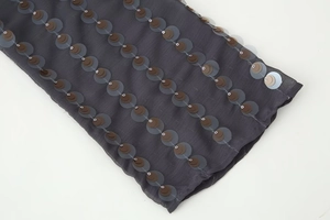 Detailed close-up showing brown and grey sequins stitched on dark grey sheer chiffon fabric