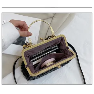 Detail view of black pleated shell bag interior holding lipstick and cosmetics