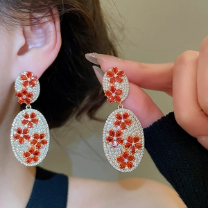 Macro detail of vintage floral oval drop earrings with red gems and zircon on model