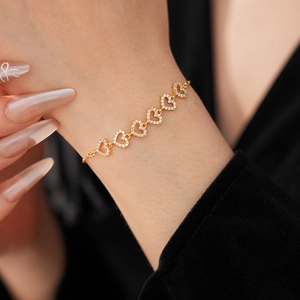 Gros plan d'un bracelet doré en forme de cœur avec fleurs en zircon au poignet