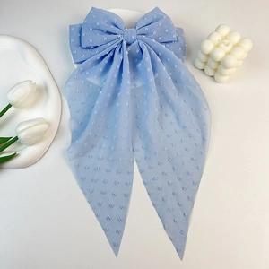 Detail of light blue Swiss dot chiffon hair bow with long ribbons and a metal spring clip