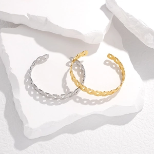 Detail of gold and silver hollow woven bangles on a minimalist white stone background
