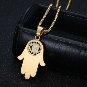 Collier main de Fatima doré avec strass bleus posé sur un écrin en cuir noir élégant