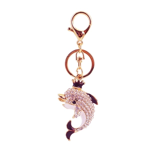 Golden dolphin keychain with crown and clear rhinestones on a white background