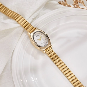 Elegant gold oval women's watch with quartz movement and metal strap on a white tray