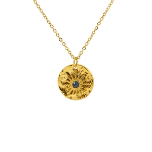 Detailed close-up of a vintage gold starburst pendant with a deep blue gemstone inlay