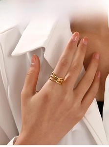 Detail shot of multi-layer crossed gold rings on model's hand with soft lighting