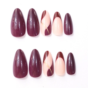 Detailed view of long almond press-on nails with purple and gold striped patterns