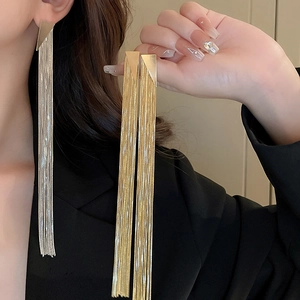 Detailed view of long gold and silver tassel earrings with triangle studs on a model