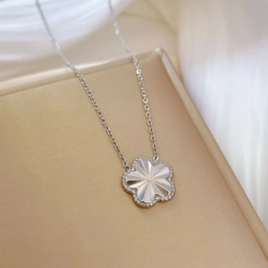 Macro shot of a titanium steel necklace featuring a 5-petal flower pendant with white inlay