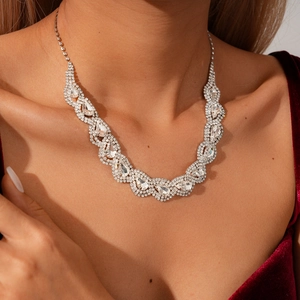 Close-up of luxury teardrop rhinestone necklace worn on neck with red velvet dress