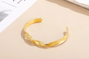 Detailed view of the twisted texture and high-shine gold finish on the stainless steel cuff