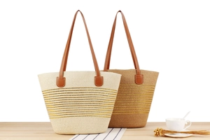 Detail of woven tote bags with gold stripes and leather straps on wooden background