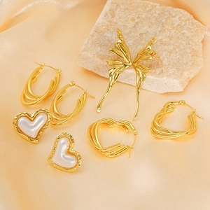 Detail of 18K gold butterfly earrings and heart studs with pearls on silk cloth