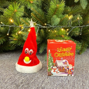 Cappello di Babbo Natale elettrico con stella LED e confezione regalo vicino all'albero