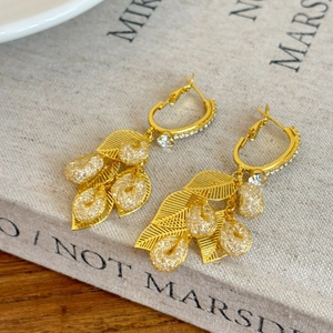 Elegant gold leaf tassel earrings with sparkling crystals displayed on a vintage book