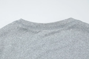 Close-up of crew neck stitching and grey knitted cotton fabric texture of the top
