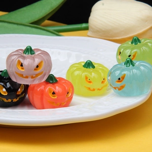 Colorful resin Halloween pumpkin charms with smiling faces on a white embossed plate