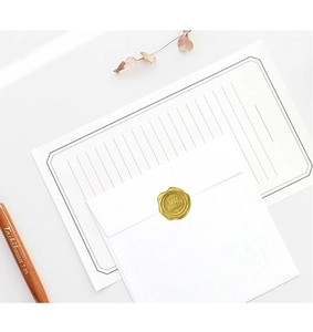 Detail of vintage gold wax seal sticker on white envelope with dried flower decor