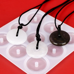 Close-up of three jade-like stone pendants on a silicone mold with red background