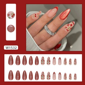 Detailed view of almond-shaped press-on nails with red glitter and cherry patterns