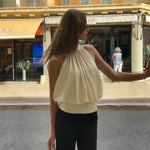 Schickes beiges Neckholder-Plissee-Top für Damen kombiniert mit schwarzer Hose im Freien