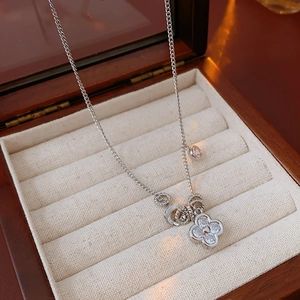 Primo piano di una collana con ciondolo a fiore argento e gemme in un portagioie di legno