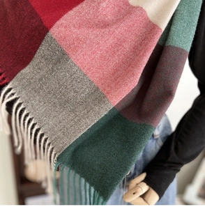 Detailed close-up of plaid cashmere feel scarf with colorful blocks and white tassels