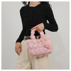 Pink quilted handbag featuring golden bow detail and soft faux fur pom-pom charm