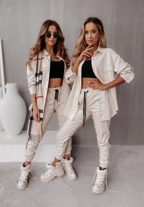 Dettaglio della tuta in ecopelle bianco crema con pantaloni jogger e giacca corta