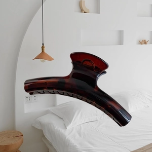 Large 15cm tortoise shell claw clip floating in a minimalist neutral bedroom setting