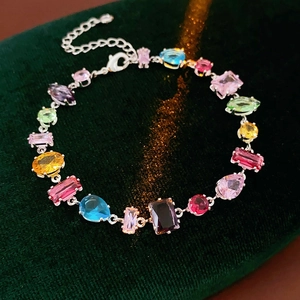 Detailed close-up of a colorful gemstone bracelet on a luxury green velvet background