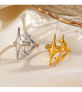 Detail of star-shaped rings in gold and silver finish on a soft fabric backdrop