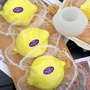 White silicone lemon mold and realistic yellow fruit candles on wooden tray