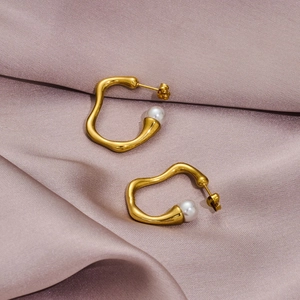 Irregular gold-plated stainless steel pearl earrings displayed on purple satin background