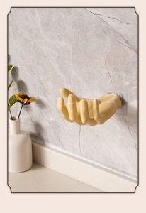 Creative thumb-up wall hook in yellow resin holding keys on a marble surface