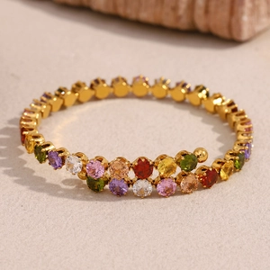 Macro detail of 18K gold-plated bangle with colorful cubic zirconia on stone background