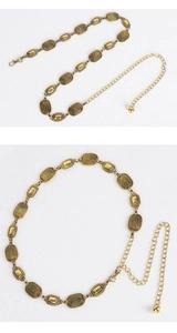 Détail d'une ceinture chaîne en métal doré vintage avec boucles ovales et pendentif boule
