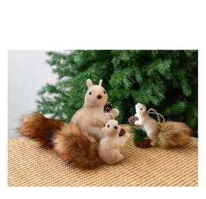 Detail of Christmas squirrel ornaments with faux fur tails and pinecones on a tree branch