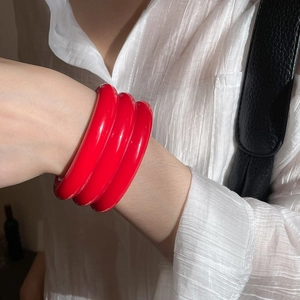 Detailed view of triple red resin bangles set on wrist for a layered fashion look