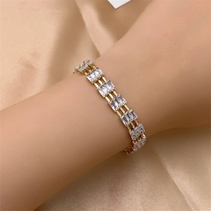 Close-up of golden triple-row bracelet with rectangular zircon stones on champagne satin
