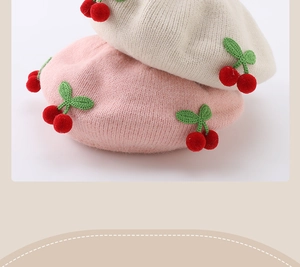 Detailed knit texture of baby beret featuring soft 3D cherry accents in cream and pink
