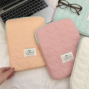 Detailed view of heart-quilted laptop sleeves in pastel pink, orange, and mint green