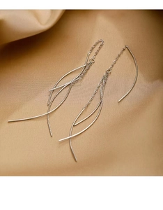 Macro detail of silver tassel earrings with layered curved lines on champagne silk fabric