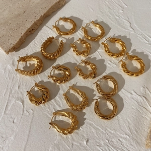Chunky gold-plated twisted hoop earrings in various sizes on minimalist stone background