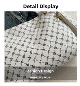 Close-up of white leather tote with black monogram pattern and gold metal hardware