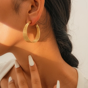 Nahaufnahme von eleganten minimalistischen mehrlagigen Goldohrringen an einem Model für Stil