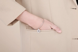 Silver stainless steel bracelet with LOVE engraved round pendant shown on model wrist
